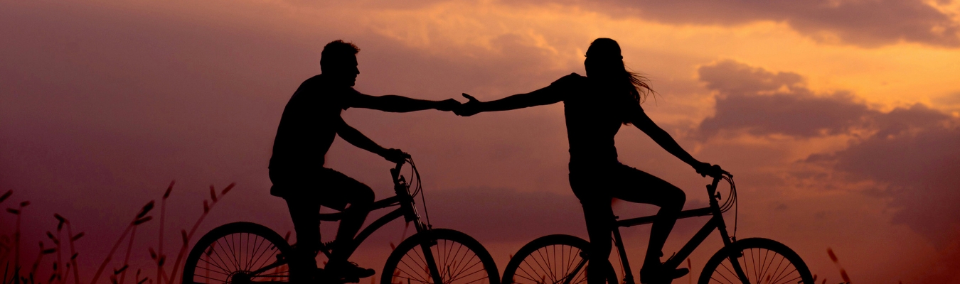 two people holding hands on bikes